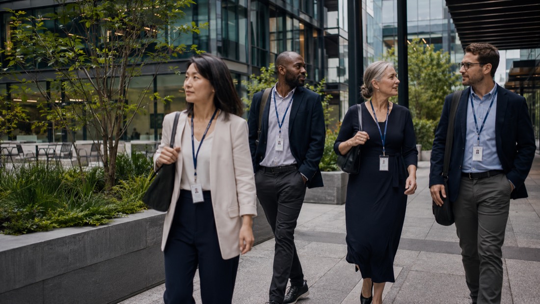 Professionals wearing ID lanyards walking outside a corporate office campus